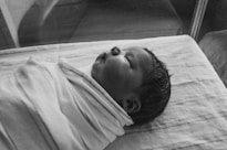 grayscale photography of sleeping baby covered by textile