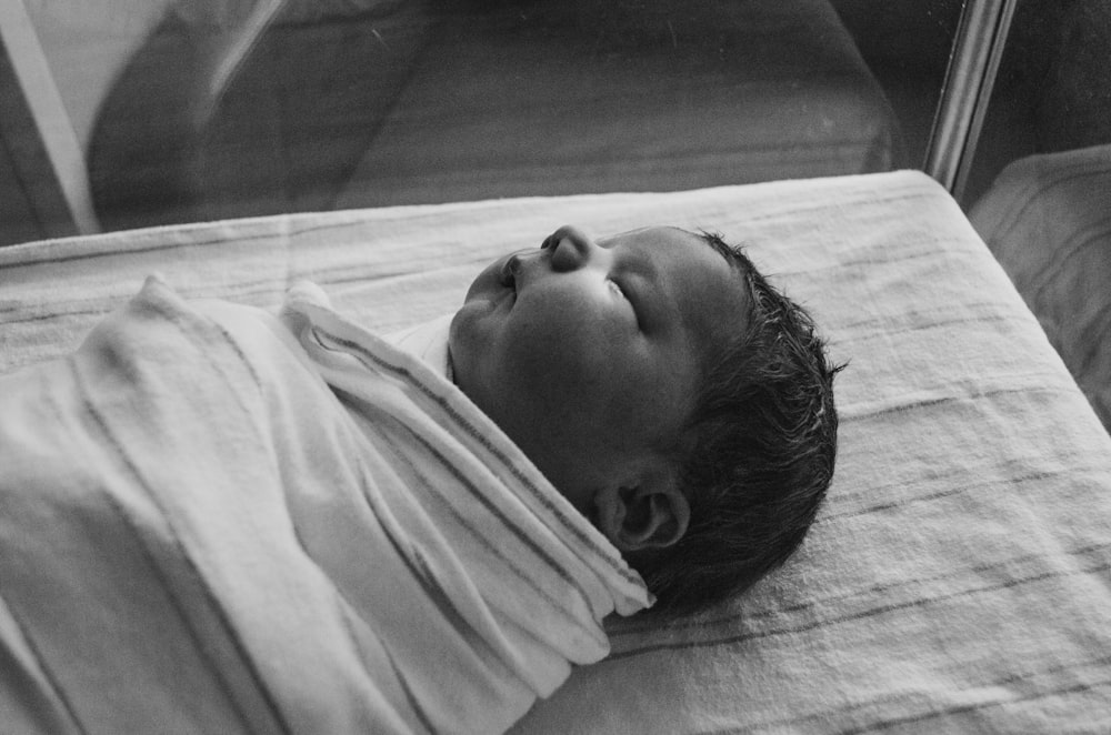 grayscale photography of sleeping baby covered by textile