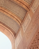 An intricately designed architectural element features detailed geometric patterns and ornate calligraphy in a symmetrical layout. The arches and carvings exhibit a high level of craftsmanship and artistry, with a focus on elegance and precision.