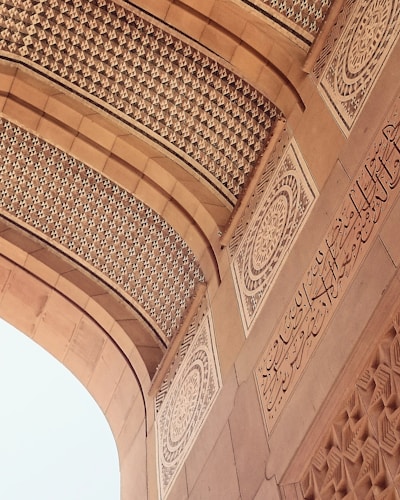 An intricately designed architectural element features detailed geometric patterns and ornate calligraphy in a symmetrical layout. The arches and carvings exhibit a high level of craftsmanship and artistry, with a focus on elegance and precision.