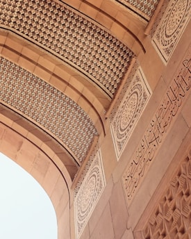 An intricately designed architectural element features detailed geometric patterns and ornate calligraphy in a symmetrical layout. The arches and carvings exhibit a high level of craftsmanship and artistry, with a focus on elegance and precision.