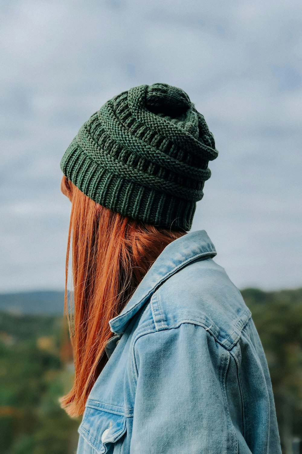 donna che indossa berretto in maglia verde e giacca di jeans blu