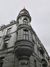A historic building with ornate architectural details, including an intricately designed turret topped with a red dome. The facade features detailed stucco work and large windows. The word 'банк' is displayed near the entrance, indicating it is a bank.