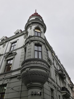 A historic building with ornate architectural details, including an intricately designed turret topped with a red dome. The facade features detailed stucco work and large windows. The word 'банк' is displayed near the entrance, indicating it is a bank.