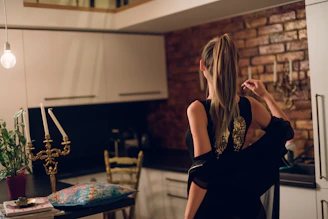 Elegant portrait of Virginia Gómez in a warm, cream-toned kitchen with golden and green accents.