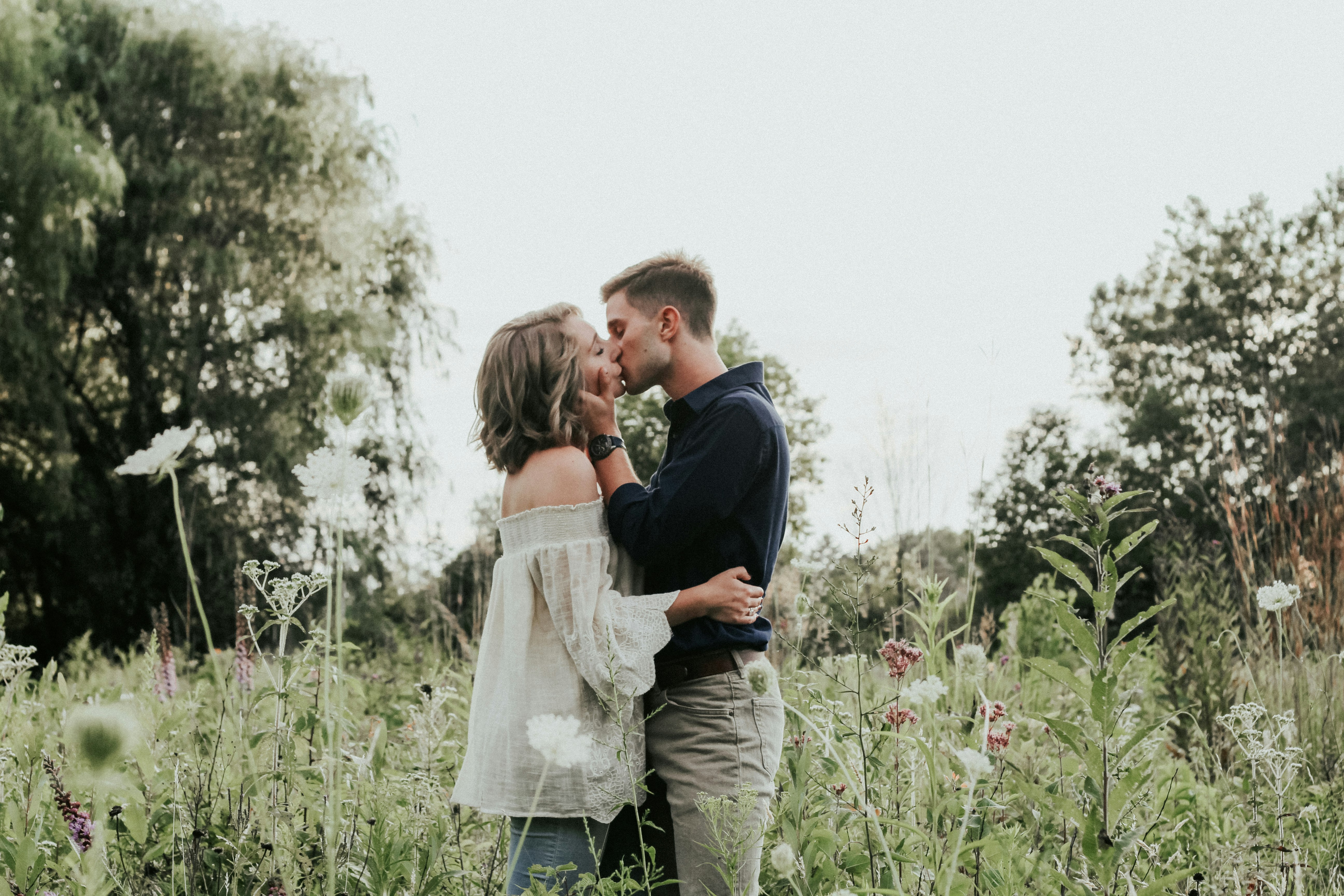 male and female kissing on grass field