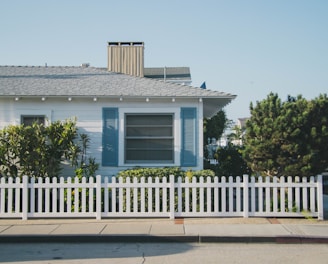 white and blue house beside fence