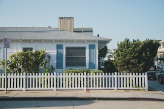 white and blue house beside fence
