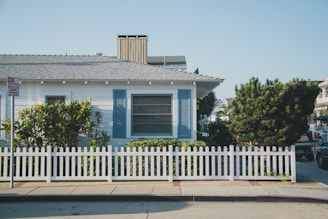 white and blue house beside fence