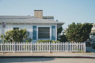 white and blue house beside fence