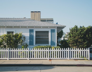 white and blue house beside fence