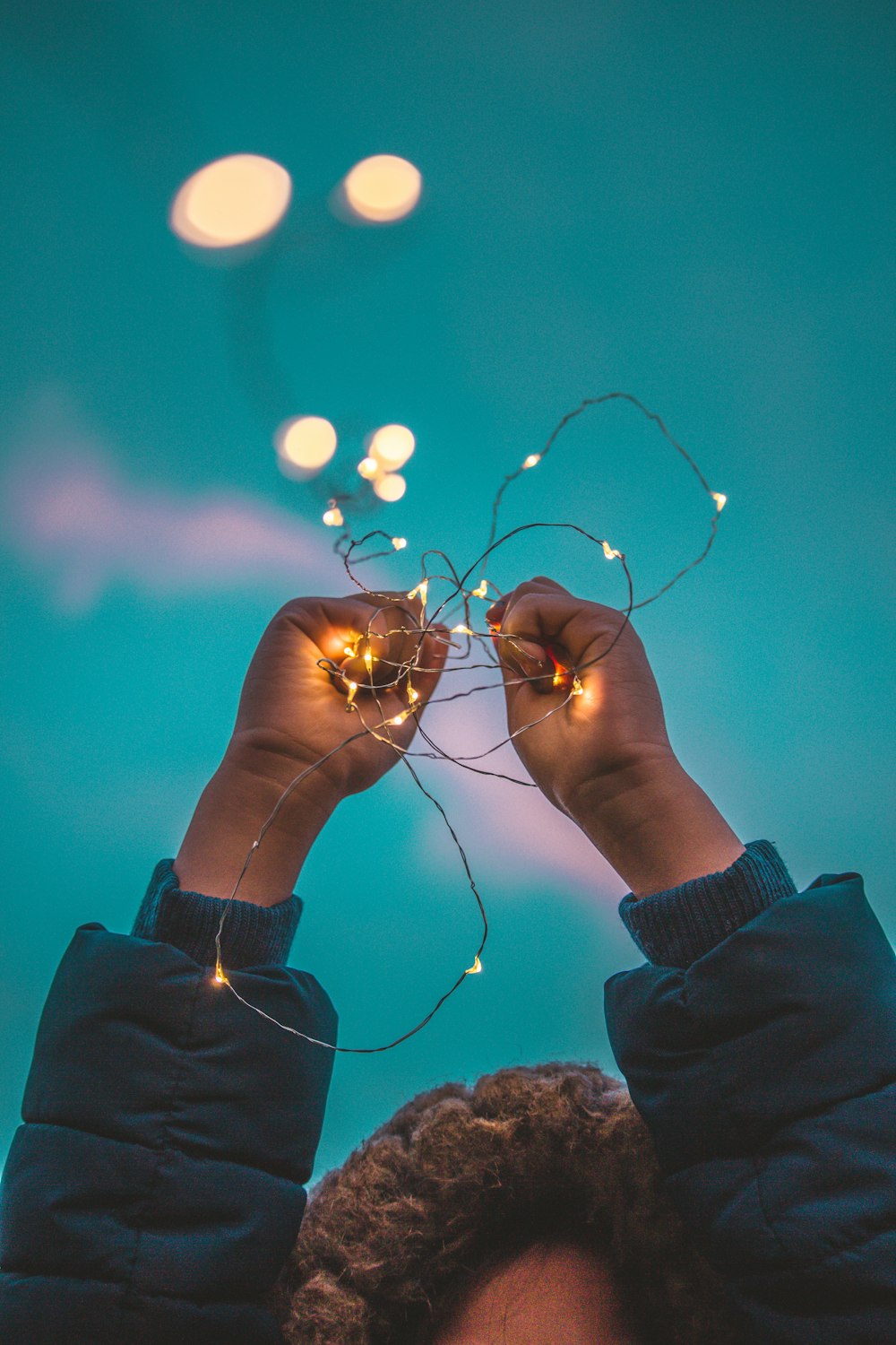 person holding up a yellow string light