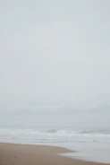 Quiet beach scene under overcast sky with distant horizon.