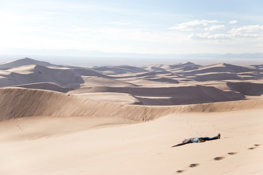 man lying on desert at daytime in Great Sand Dunes National Park and Preserve United States
