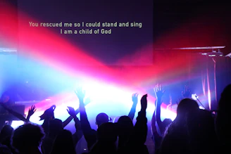 A diverse group of believers lifting hands in worship inside a warmly lit church sanctuary.