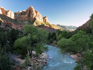 Sunlit river flowing gently through the lush Swat valley with distant mountains.