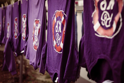 A mockup of a purple t-shirt with gold Kingdom Party emblem on the chest.