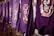 A line of purple shirts are hanging, each featuring a circular logo with the letters 'R' and 'P' surrounded by a red and white design. The shirts appear to be drying outside.