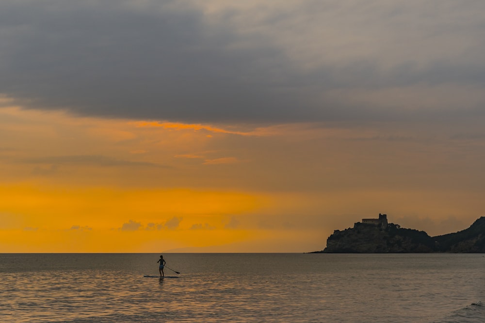 person riding on boat paddle during sunset