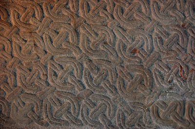 Close-up of a richly patinated Celtic coin with swirling knot patterns.