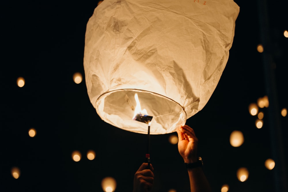 person holding sky lantern at night