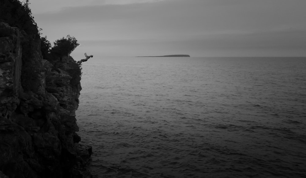 grayscale photo of hill near body of water