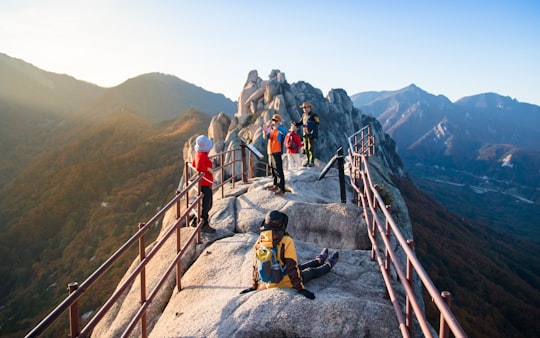 people on gray rock formation near mountains at daytime in Seoraksan South Korea