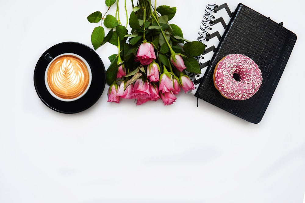 red rose flowers, pink dough nut graphic book and black ceramic cup