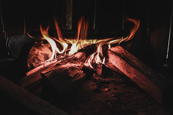 A cozy home fireplace glowing warmly with stacked pallets of pellet bags nearby.