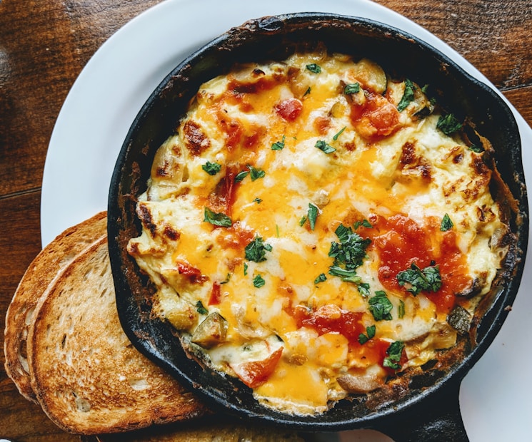 A golden baked egg frittata sliced and served on a black plate