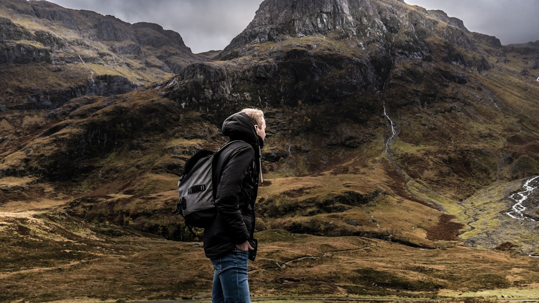 man standing in front mountain under gray sky