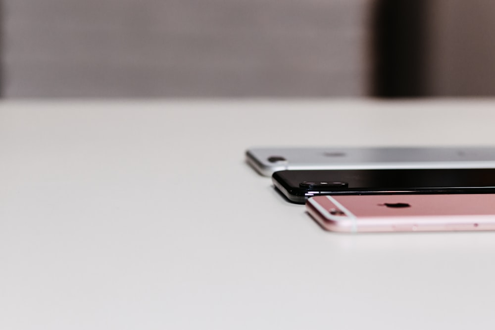 three assorted iPhones on table