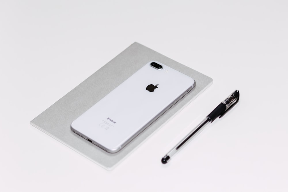 silbernes iPhone X neben schwarzem Kugelschreiber