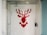 A shower area with white tiles featuring a pixelated red stag design on the back wall. The shower fixtures include a modern square showerhead and a handheld shower wand. The space is enclosed by a glass door and has a minimalist style.