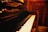 A close-up of a piano with sheet music and a warm light illuminating the keys.