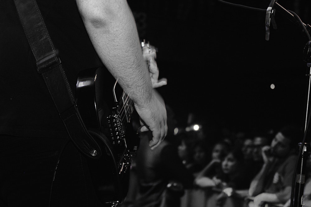 grayscale photo of person playing guitar