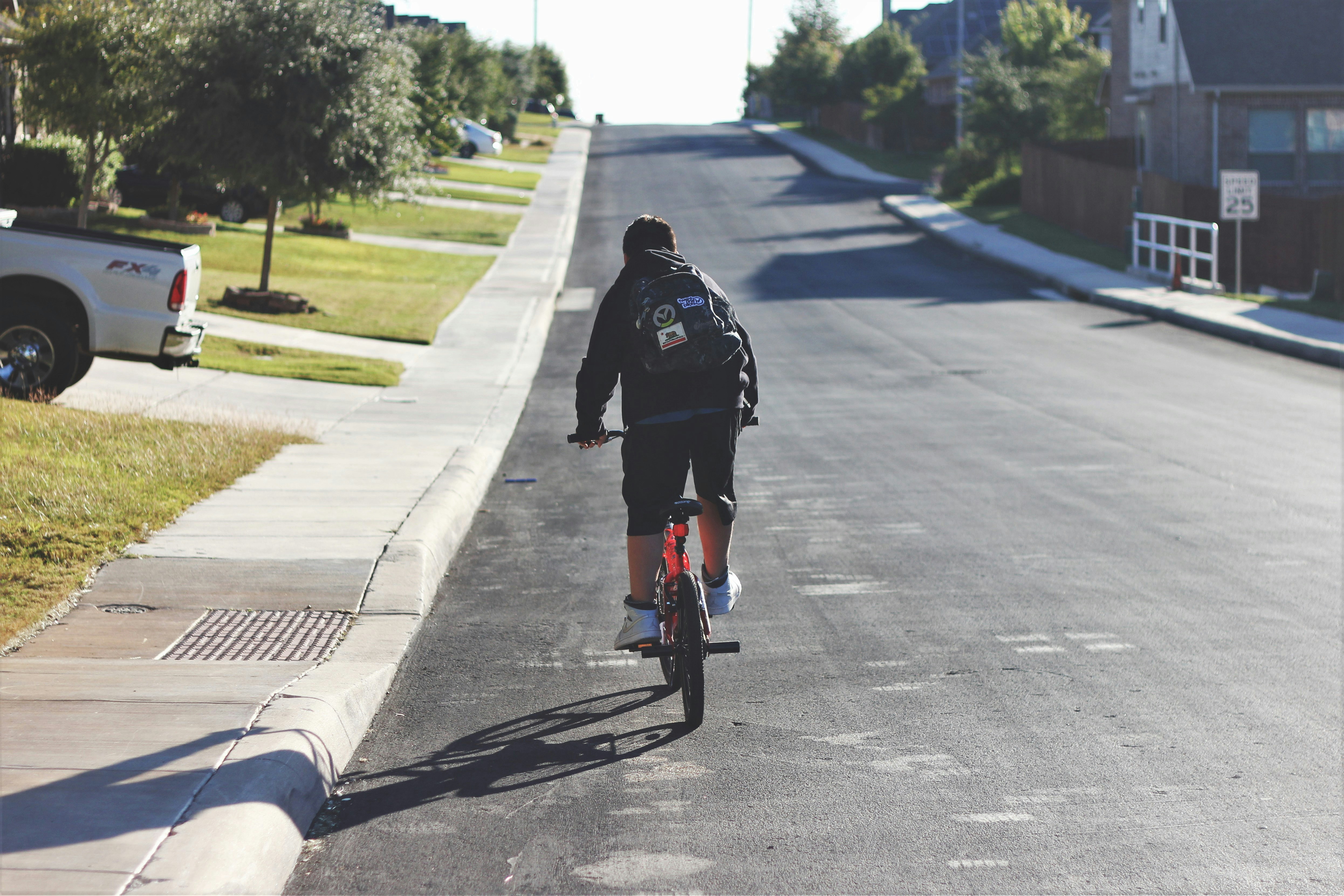 man cycling along asphalt road during daytime