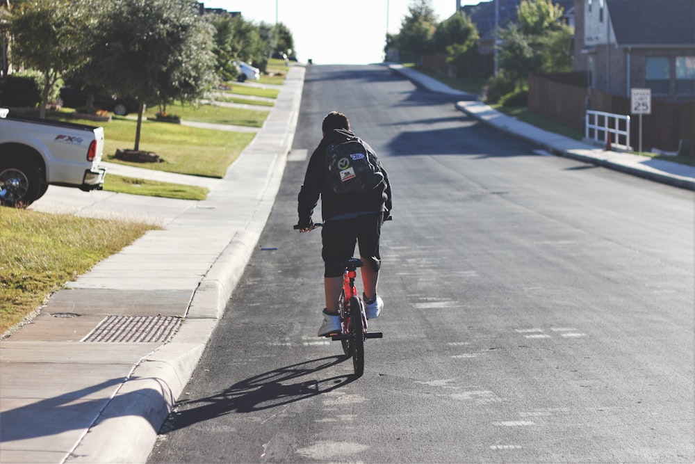 man cycling along asphalt road during daytime