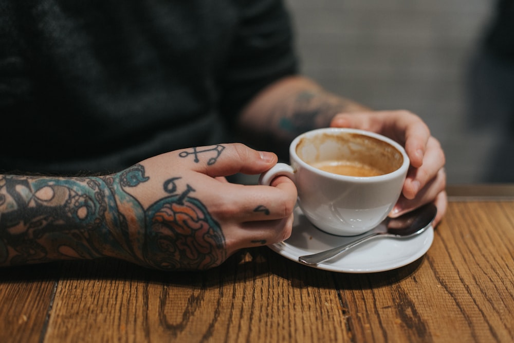 person holding white teacup on white saucer