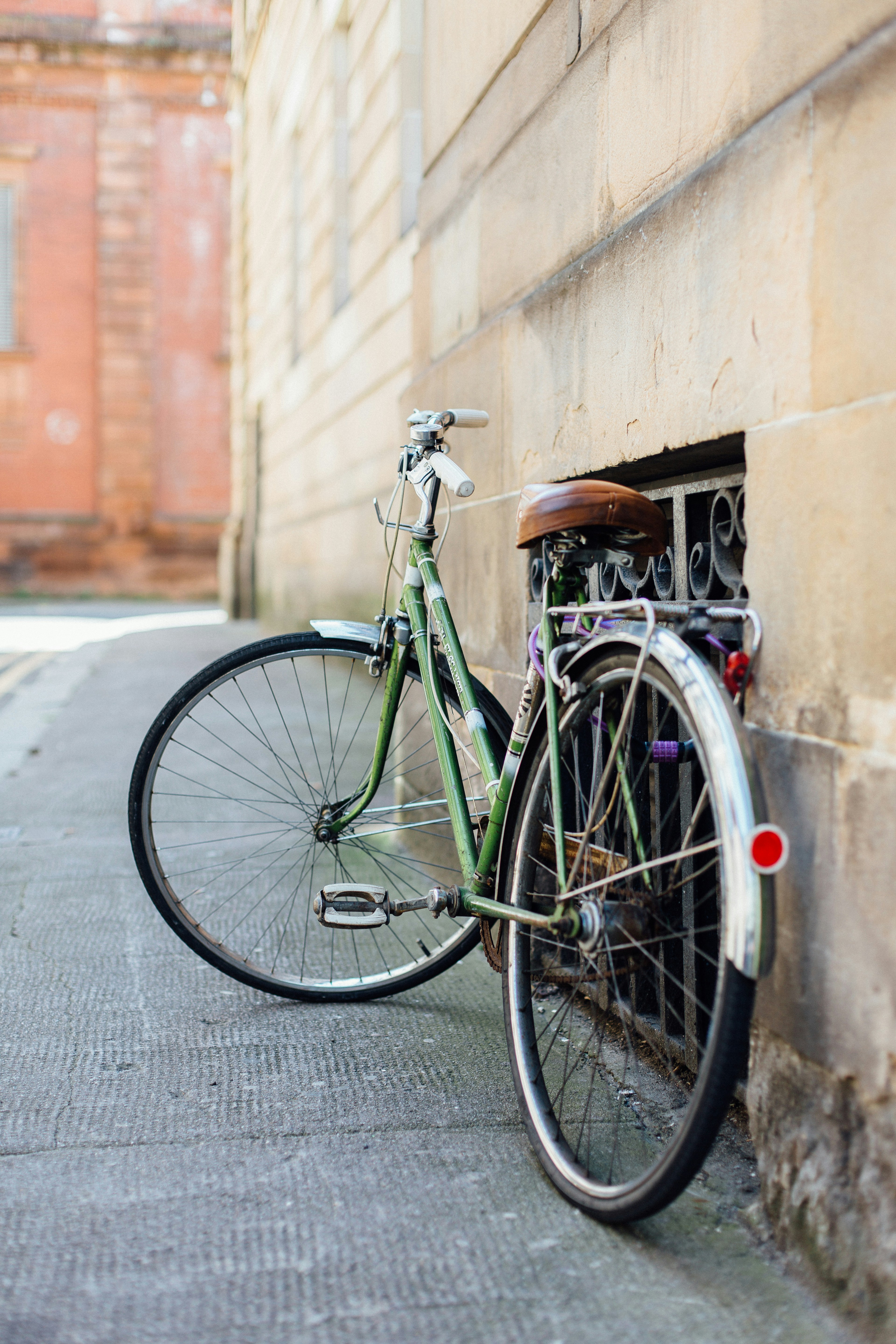 green female beach cruiser bike leaning on wall