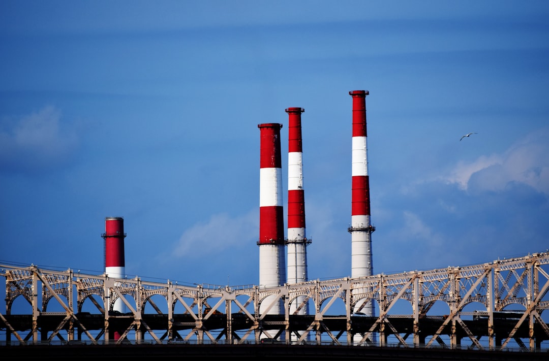 gray and black bridge across four red-and-white pipes