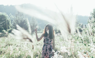 Sunlit serene meadow with models wearing light apricot pastel hippie-style clothing, evoking a Nordic-Greek inspired vibe.