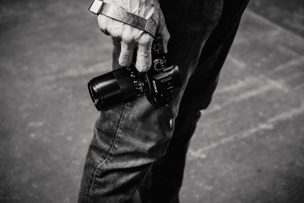 foto in scala di grigi di una persona che tiene in mano una fotocamera DSLR