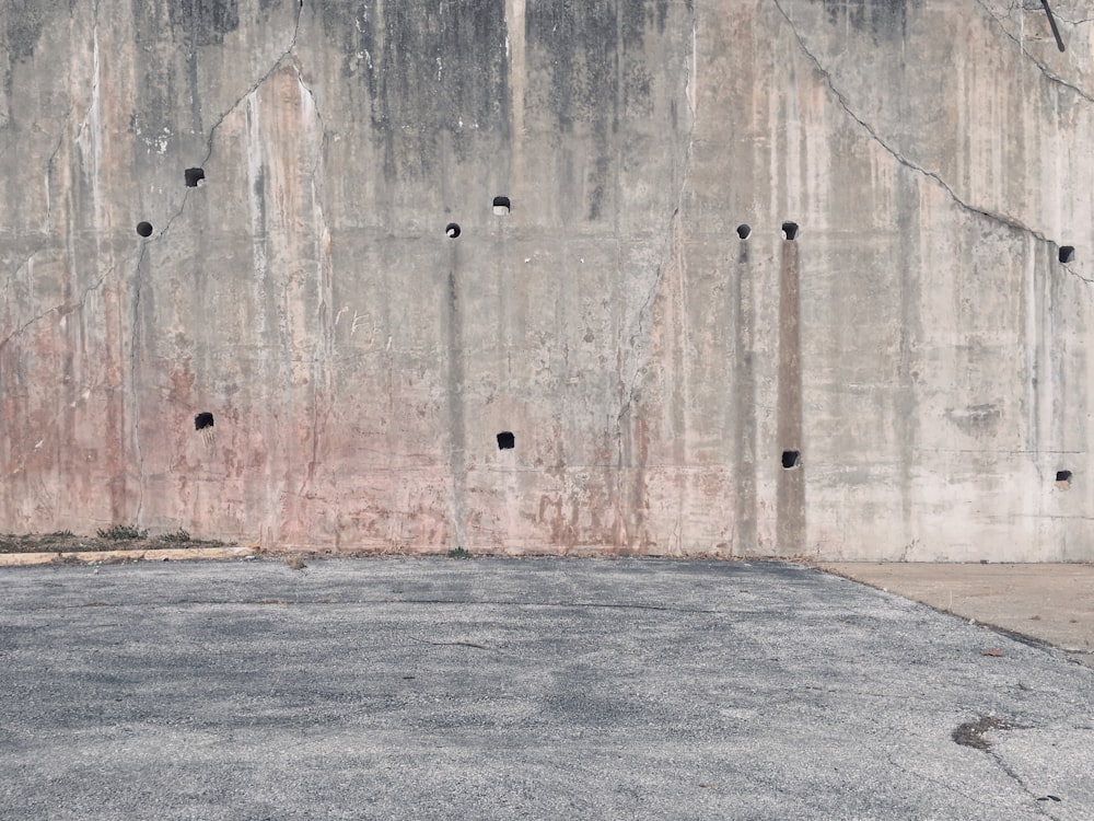 a man riding a skateboard down a street next to a cement wall