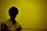 A silhouette of a person with curly hair against a yellow background, wearing a light-colored shirt.