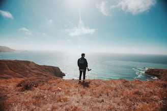 man in black jacket standing on brown grass