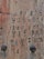 A close-up view of a wooden surface with various symbols and characters carved into it. The carvings appear to be of different styles, possibly representing a code or message. The wood has a weathered texture with horizontal grains and a few dark, rounded objects embedded in it.