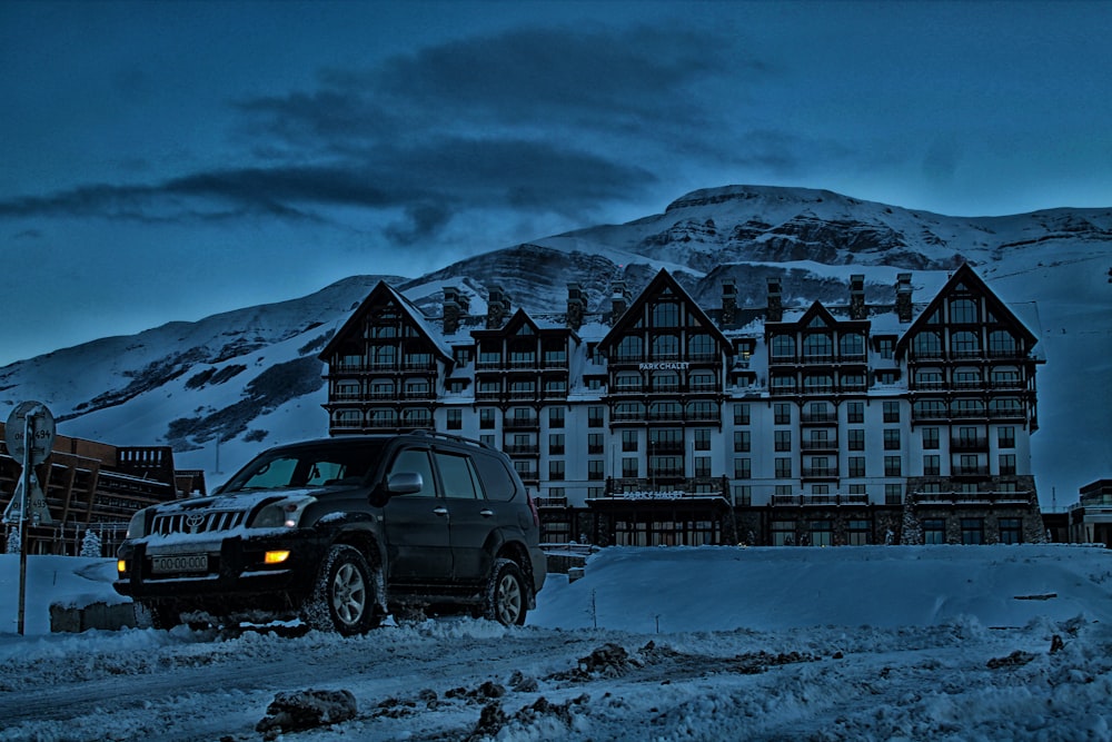 SUV estacionado en el edificio delantero con fondo de montaña