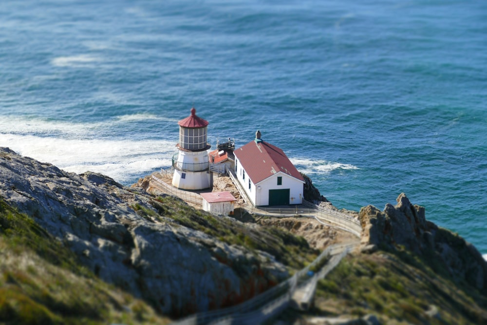 Maison blanche et rouge et phare près de la mer pendant la journée