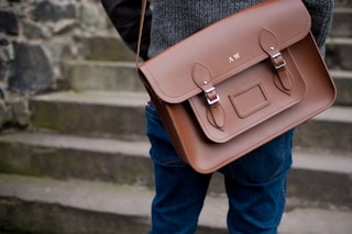 person carrying brown leather shoulder bag